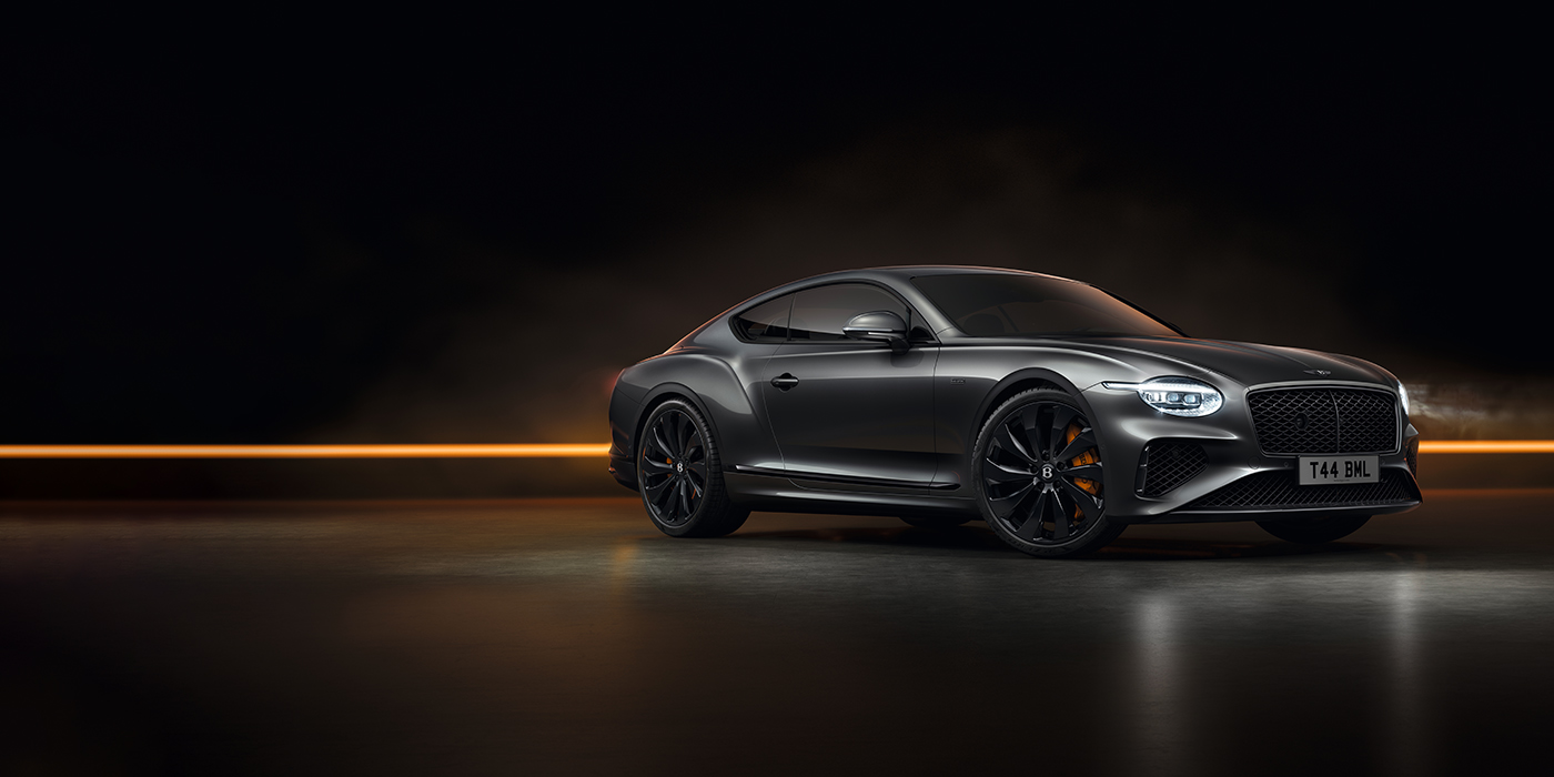 Emil Frey Exclusive Cars GmbH | Bentley München Bentley Continental GT Black Edition coupe front three quarter in Anthracite black paint against a dark grey and copper background