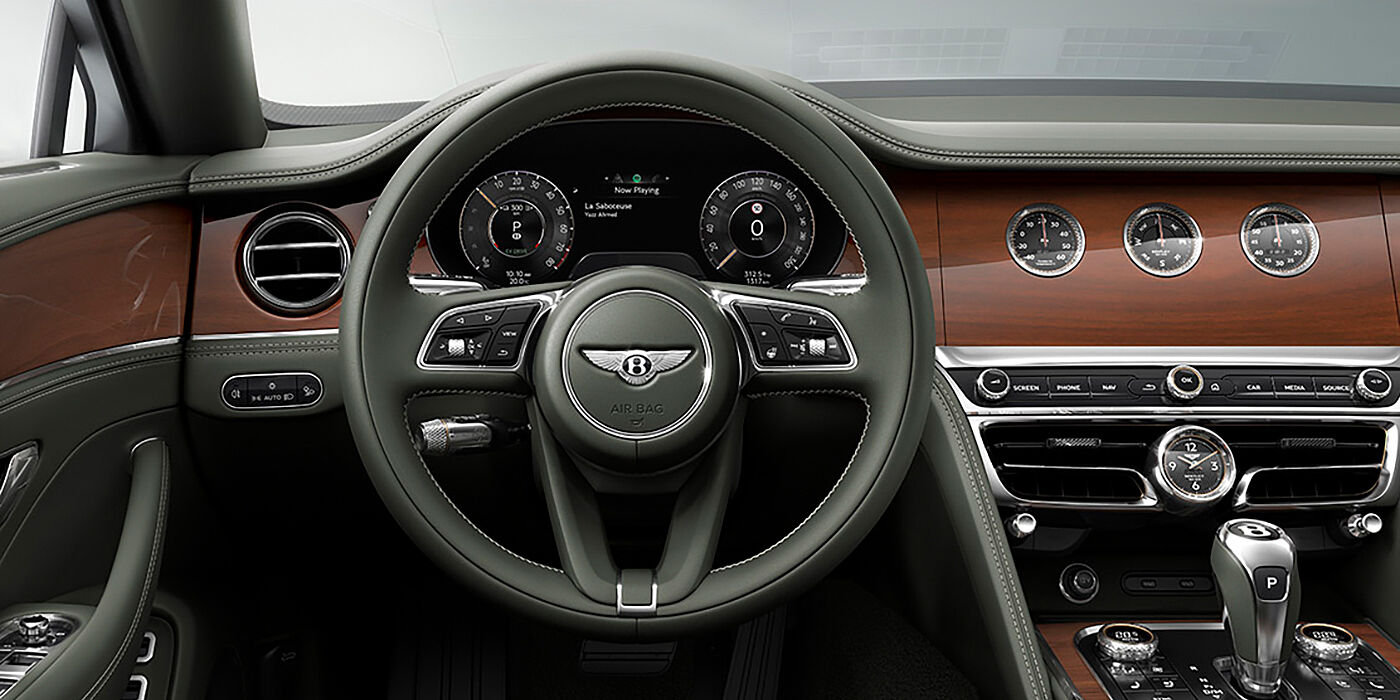 Emil Frey Exclusive Cars GmbH | Bentley München New Bentley Flying Spur sedan front cabin in Cumbrian Green hide and Crown Cut walnut veneer showing steering wheel and Rotating Display with three clocks on face