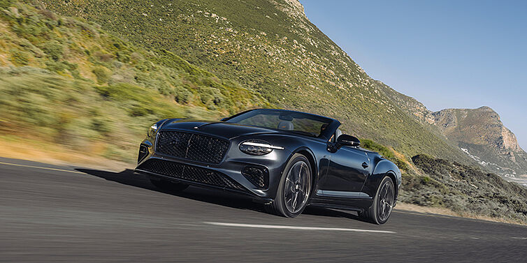 Emil Frey Exclusive Cars GmbH | Bentley München Bentley Continental GTC S convertible in Thunder paint front 3/4 driving on mountain road