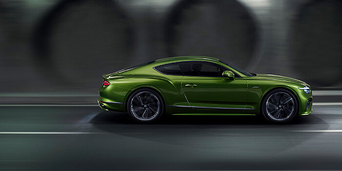  Emil Frey Exclusive Cars GmbH | Bentley München Bentley Continental GT coupe in Tourmaline Green paint driving in profile on a dark road