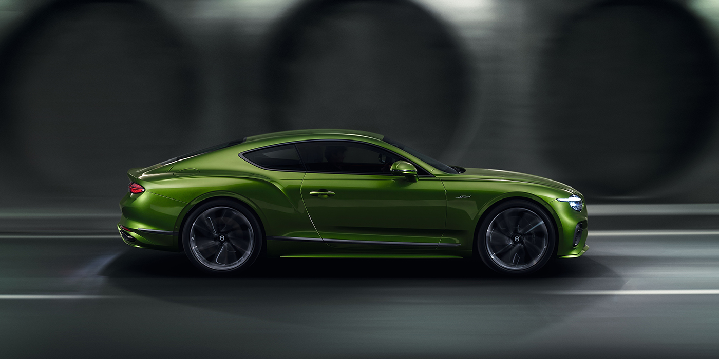 Emil Frey Exclusive Cars GmbH | Bentley München Bentley Continental GT coupe in Tourmaline Green paint driving in profile on a dark road